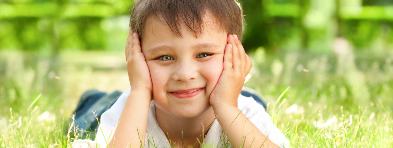 Boy laying in grass Pediatric Dentist Dr. Rex Wildey in Kerrville, TX.